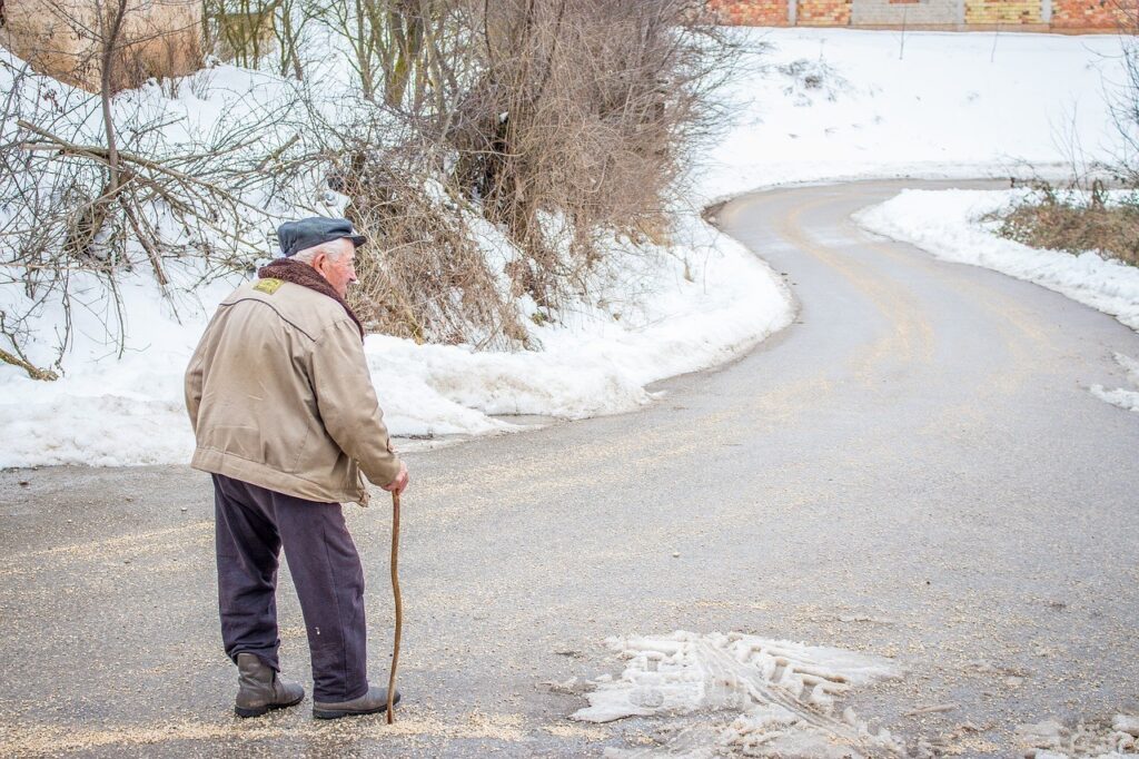Elderly Man walking down the road in the winter