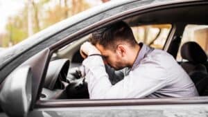 Man with head on steering wheel